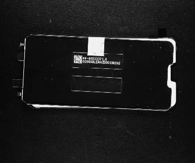 Source white-bar image: the marked serial region is visible on the dark cover while its outer edge reflects brightly.