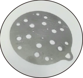 The test part: a circular machined metal plate with drilled holes.
