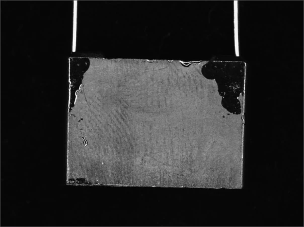 Source white diffuse-ring capture: dark irregular regions contrast with the lighter rectangular component face.